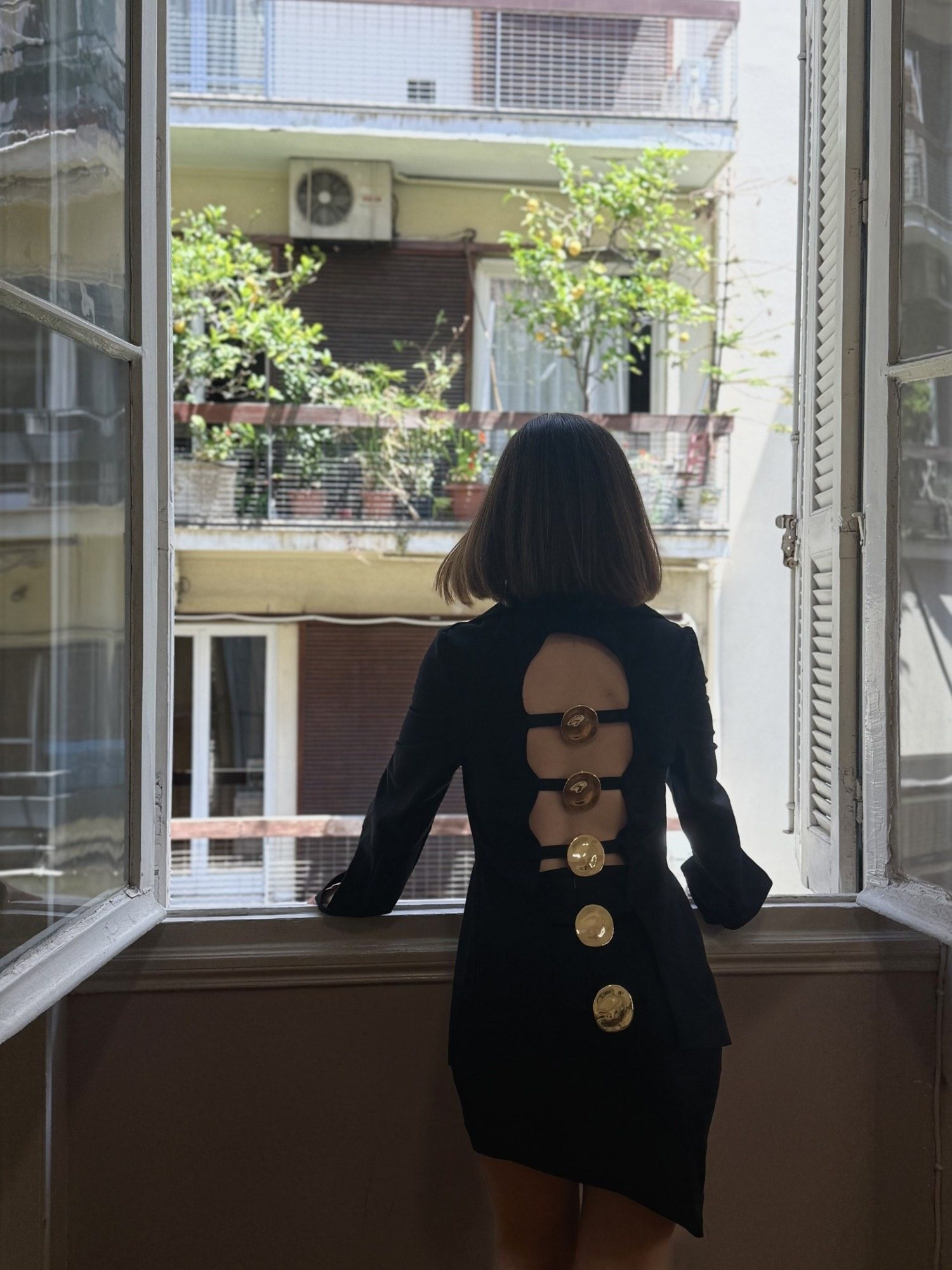 Ponte jacket from the back: arched cut-out bridged by straps with sculpted gold buttons